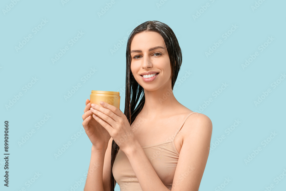 Beautiful young happy woman with jar of hair mask on blue background Beautiful young happy woman with jar of hair mask on blue background