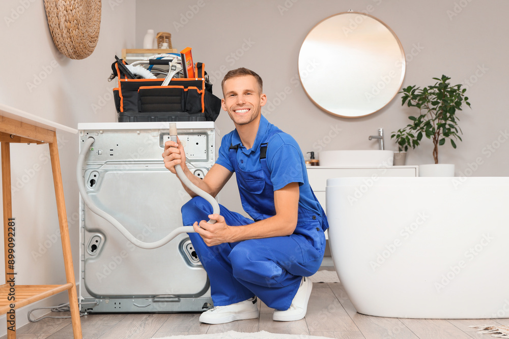 Male plumber repairing washing machine in bathroom Male plumber repairing washing machine in bathroom