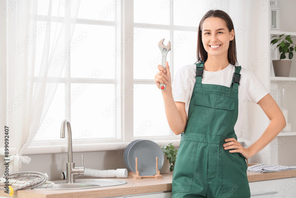 Female plumber with wrench near sink in kitchen Female plumber with wrench near sink in kitchen