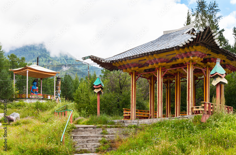 Naklejka premium Siberia, Buryatia. Park area in the resort village of Arshan with an oriental gazebo and a sculpture of medical Buddha on a hill in the foothills of the Tunka Valley on a foggy summer day