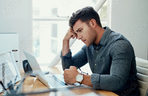 Stress, laptop and business man reading bad news for debt or bankruptcy at creative startup. Computer, mistake and sad employee with email for taxes, fail or thinking of challenge with job rejection photo