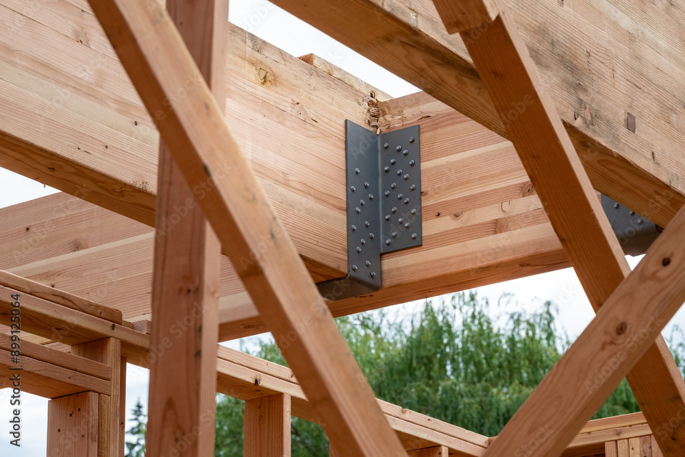 Obraz premium Closeup detail of new house construction, large glue laminate support beams connected by black metal brackets 