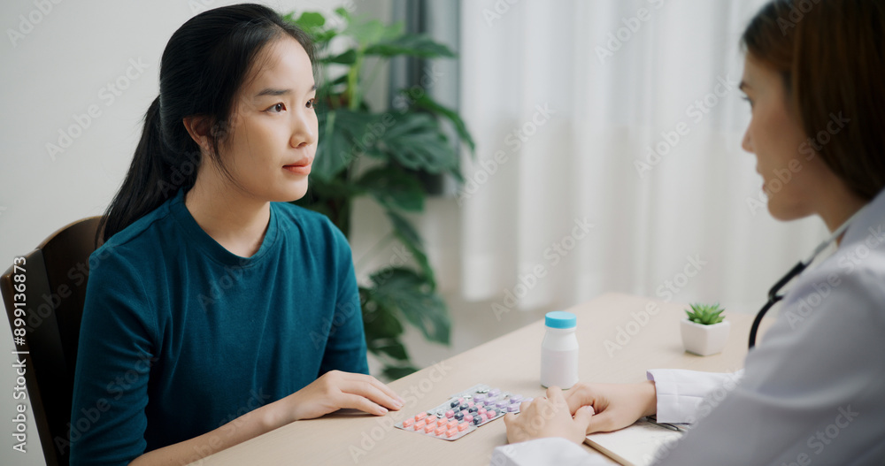 Selective focus, Asian doctor explaining how to take medicine to young female patient in clinic office, Health and medicine consultant, Conversation about healthcare Selective focus, Asian doctor explaining how to take medicine to young female patient in clinic office, Health and medicine consultant, Conversation about healthcare