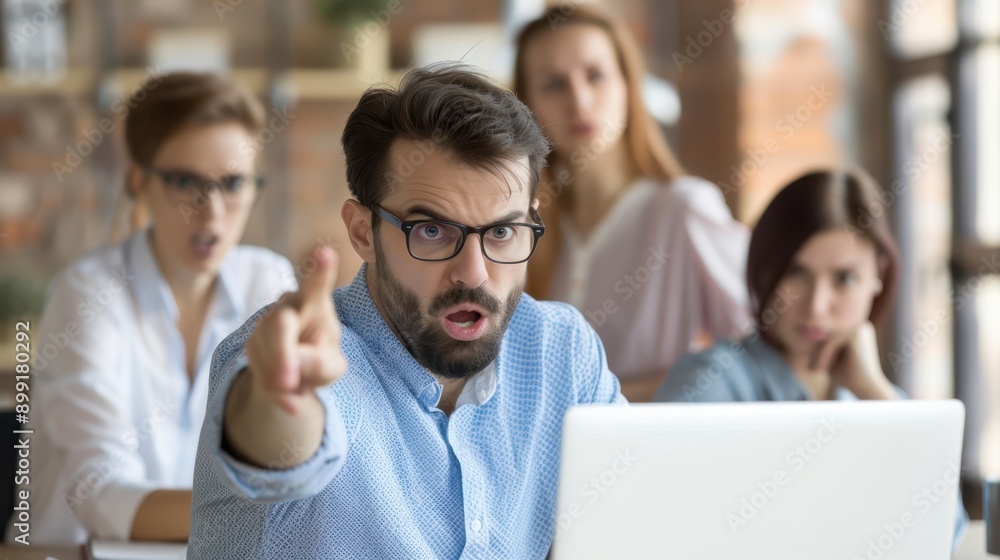 Frustrated Office Worker Pointing at Malfunctioning Laptop, Colleagues Offering Support in Background Frustrated Office Worker Pointing at Malfunctioning Laptop, Colleagues Offering Support in Background