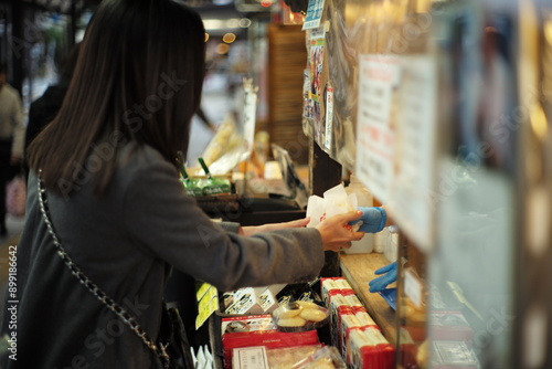 Woman buys the food from shop. Deliver the snack in front of the stall.