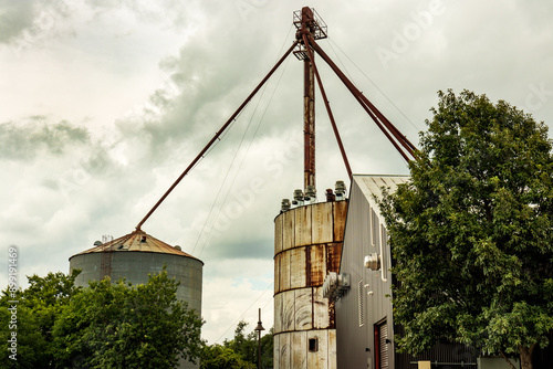 A historic mill and grain facility in Buda, Texas, featuring a large, cylindrical grain silo with a corrugated metal exterior.  This image is ideal for searches related to historic mills, grain silos.