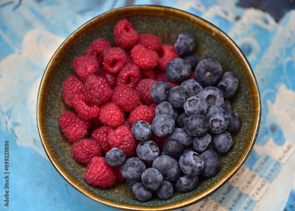 raspberries and blueberries and in a bowl raspberries and blueberries and in a bowl