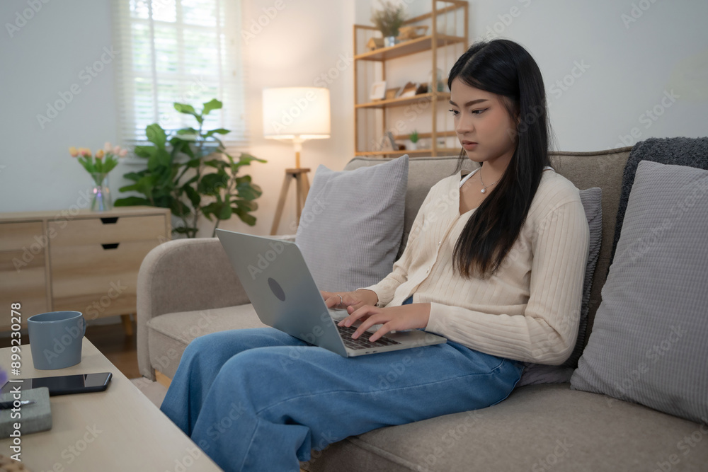 Young asian women putting laptop on legs and typing business report about marketing data of new startup while sitting on the couch to spending time and relaxation with enjoying lifestyle at home Young asian women putting laptop on legs and typing business report about marketing data of new startup while sitting on the couch to spending time and relaxation with enjoying lifestyle at home