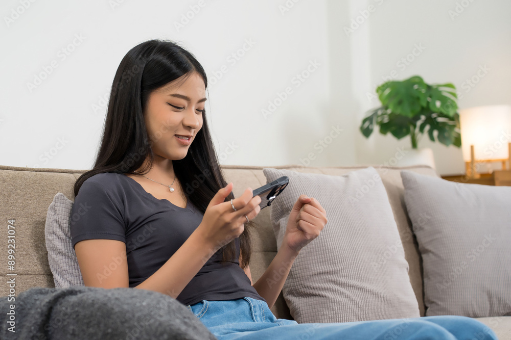 Young asian gamer women using smartphone to playing video game with having fun and happiness while sitting on comfortable couch to spending time and relaxation with enjoying lifestyle at home Young asian gamer women using smartphone to playing video game with having fun and happiness while sitting on comfortable couch to spending time and relaxation with enjoying lifestyle at home