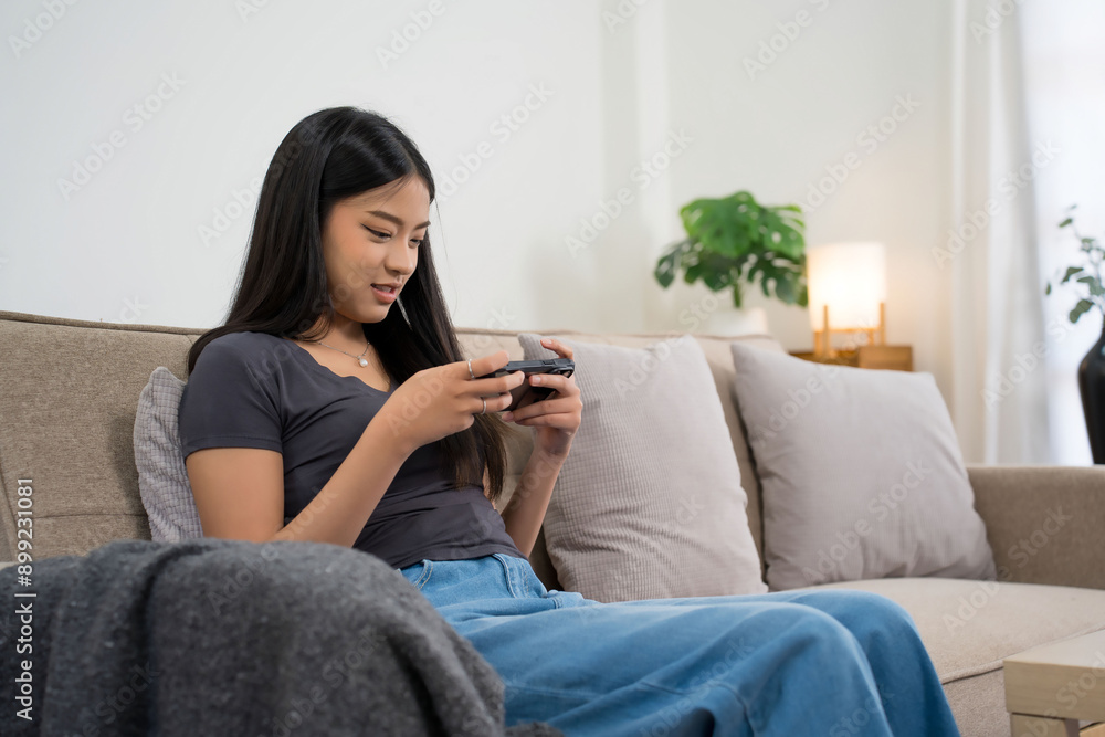 Young asian gamer women using smartphone to playing video game with having fun and happiness while sitting on comfortable couch to spending time and relaxation with enjoying lifestyle at home Young asian gamer women using smartphone to playing video game with having fun and happiness while sitting on comfortable couch to spending time and relaxation with enjoying lifestyle at home