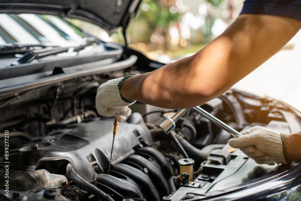 Close-up of Car mechanic noting repair parts during open car hood engine repair unrecognisable man wearing gray glove inspecting car engine and interior Close-up of Car mechanic noting repair parts during open car hood engine repair unrecognisable man wearing gray glove inspecting car engine and interior