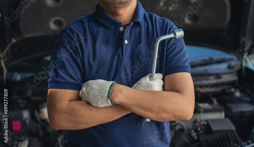 Close-up of mechanic Car Cross your arms noting repair parts during open car hood engine repair unrecognisable man wearing gray glove inspecting car engine and interior of hood of car.  photo