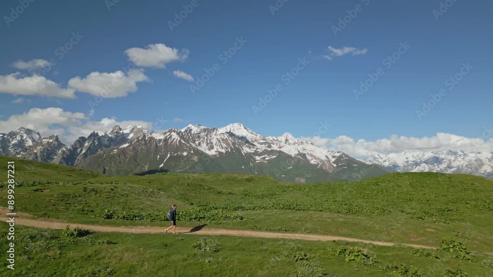 Aerial view of man trekking in alpine meadows, Svaneti mountains. Solo traveler walks scenic path, surrounded by serene landscape. Concept of depression, loneliness, adventure, exploration. Drone shot Aerial view of man trekking in alpine meadows, Svaneti mountains. Solo traveler walks scenic path, surrounded by serene landscape. Concept of depression, loneliness, adventure, exploration. Drone shot