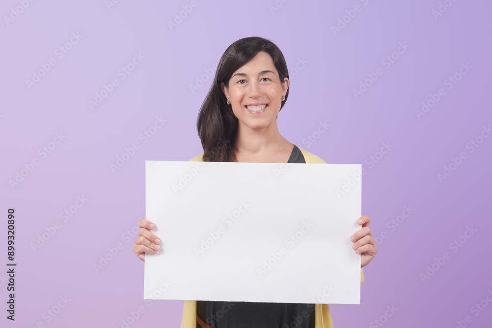 Smiling professional female professional showing white blank banner blank for business advertising and looking at camera isolated on purple background. Smiling professional female professional showing white blank banner blank for business advertising and looking at camera isolated on purple background.