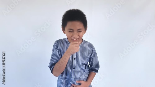 Asian little kid boy wearing blue shirt standing indoor feeling unwell and coughing as symptom for cold or bronchitis. Healthcare concept.