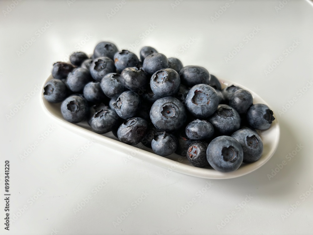 Delicious juicy blueberries isolated on white background. Black blueberries on white saucer. Tasty and healthy food Delicious juicy blueberries isolated on white background. Black blueberries on white saucer. Tasty and healthy food