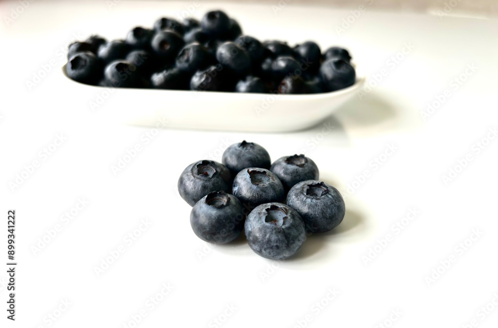 Delicious juicy blueberries isolated on white background. Black blueberries on white saucer. Tasty and healthy food Delicious juicy blueberries isolated on white background. Black blueberries on white saucer. Tasty and healthy food