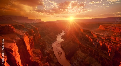 A beautiful sunset over a canyon with a river running through it. The sky is filled with clouds and the sun is setting, casting a warm glow over the landscape. The scene is serene and peaceful