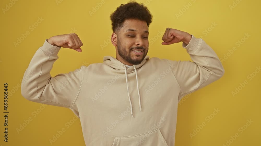Fit african american male flexing powerful muscles in yellow hoodie, basking in positive energy of healthy lifestyle success on isolated background, smiling with confidence Fit african american male flexing powerful muscles in yellow hoodie, basking in positive energy of healthy lifestyle success on isolated background, smiling with confidence