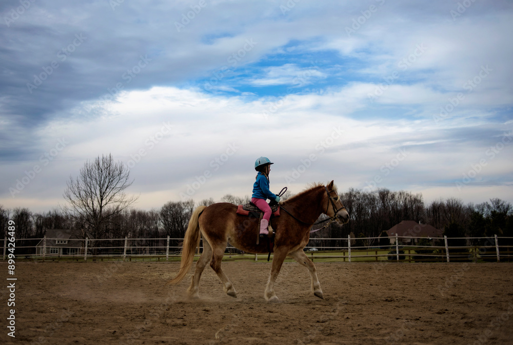 Young girl in helmet riding brown pony in pature Young girl in helmet riding brown pony in pature