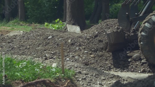 Heavy machine pushing and leveling building material during road works, close-up photo