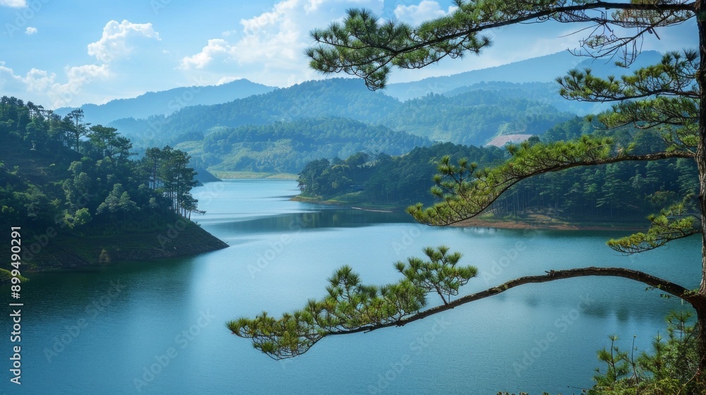 Tranquil landscape with deep blue lake, green mountains, blue sky, white clouds, and a pine branch framing the foreground, highlighting natural beauty. Tranquil landscape with deep blue lake, green mountains, blue sky, white clouds, and a pine branch framing the foreground, highlighting natural beauty.