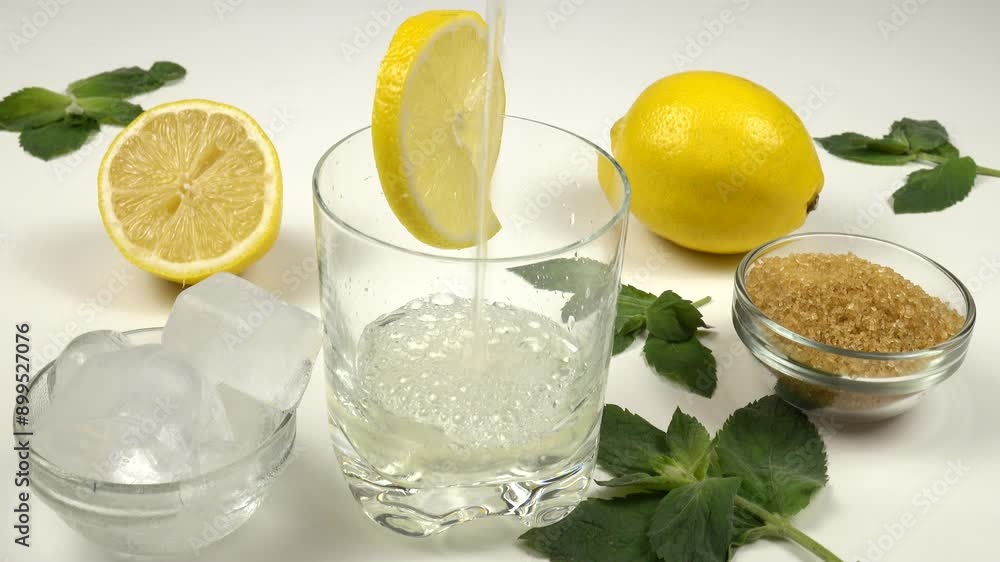 Freshly prepared homemade lemonade is poured into a glass. Ingredients for making lemonade, lemons, mint leaves and sugar. Freshly prepared homemade lemonade is poured into a glass. Ingredients for making lemonade, lemons, mint leaves and sugar.