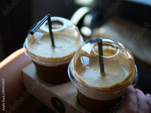 Two cold coffees with black straws in plastic cups stand in cup holders, ready to refresh. These cold coffees are perfect for cooling down and savoring a delicious, iced beverage.Refreshing effect