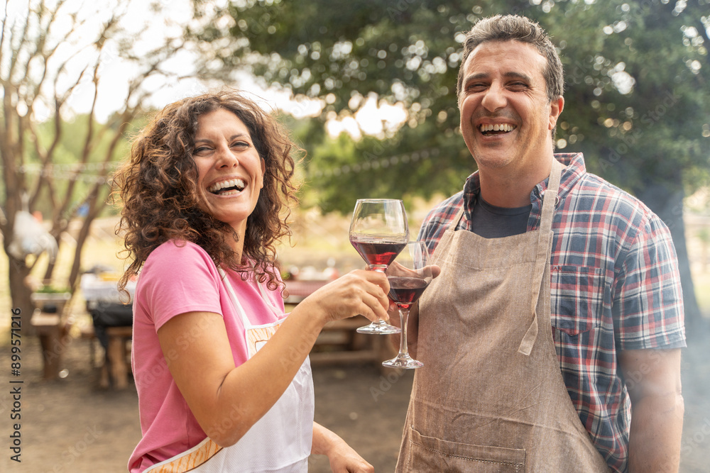 Happy couple enjoying wine while barbecuing outdoors, lifestyle and romance concept Happy couple enjoying wine while barbecuing outdoors, lifestyle and romance concept