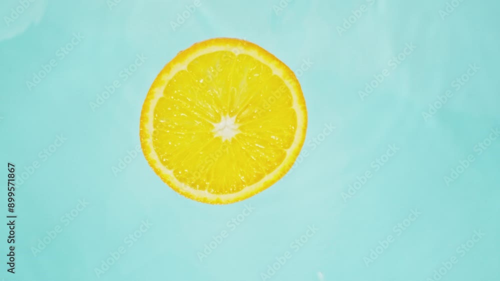 Super Slow Motion of Falling Orange Slice into Water, Blue Background. Filmed on High Speed Cinema Camera, 1000 fps. Camera Tracking the Target. Super Slow Motion of Falling Orange Slice into Water, Blue Background. Filmed on High Speed Cinema Camera, 1000 fps. Camera Tracking the Target.