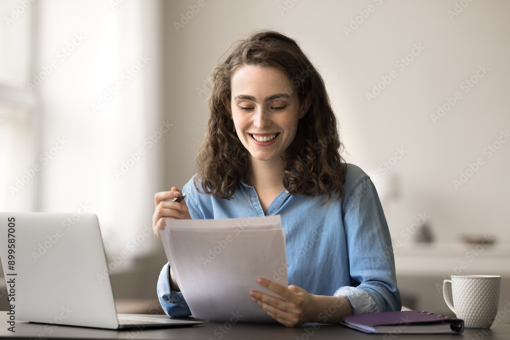 Smiling attractive student woman sit at desk with laptop, read essay, makes correction, feels satisfied with work done, prepare for session, working on diploma, filling form, doing examination test Smiling attractive student woman sit at desk with laptop, read essay, makes correction, feels satisfied with work done, prepare for session, working on diploma, filling form, doing examination test