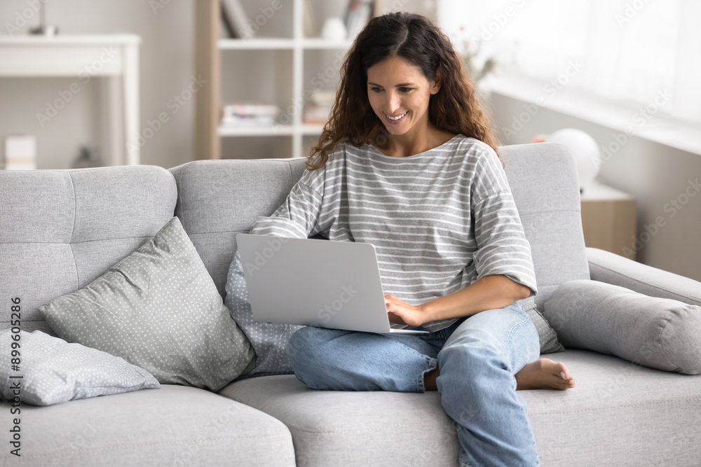 Woman sit on sofa with modern laptop, browsing wireless internet, enjoy on-line shopping, reading news, working or studying remotely, researching information, participating in online courses at home Woman sit on sofa with modern laptop, browsing wireless internet, enjoy on-line shopping, reading news, working or studying remotely, researching information, participating in online courses at home