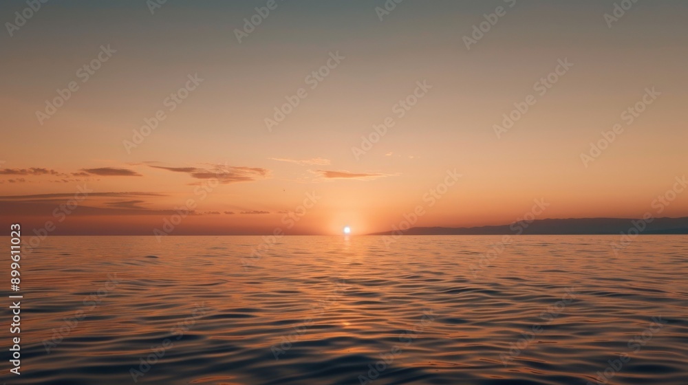 Serene sunset over calm ocean waters with gentle waves, reflecting the vibrant orange hues of the sky.