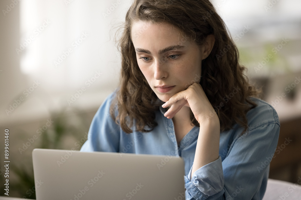 Close up serious pretty woman looks at laptop screen, ponder on answer, lead correspondence to client working remotely at home office. Student girl using internet resources studying, e-learns on-line Close up serious pretty woman looks at laptop screen, ponder on answer, lead correspondence to client working remotely at home office. Student girl using internet resources studying, e-learns on-line