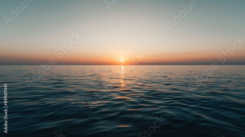 Sunset over calm ocean waters with soft ripples and a warm sky, creating a serene and tranquil scene.