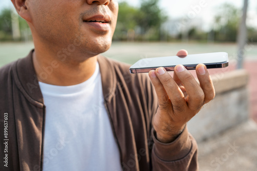 Young asian blind man using application on mobile phone to helping accessibility for persons with visual impairment. Technology for blind people sending voice message or navigation. photo