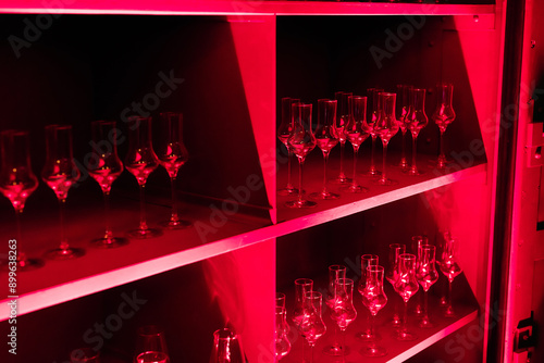 Shelf with Numerous Glasses Illuminated by Red Light