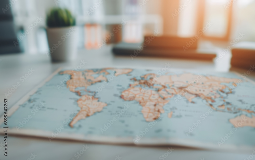 Blurred world map on a desk with sunlight streaming in, evoking a sense of adventure and exploration, perfect for travel and education themes. Blurred world map on a desk with sunlight streaming in, evoking a sense of adventure and exploration, perfect for travel and education themes.