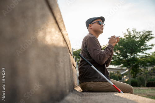 Tableau sur toile Young asian blind man using application on mobile phone to helping accessibility for persons with visual impairment