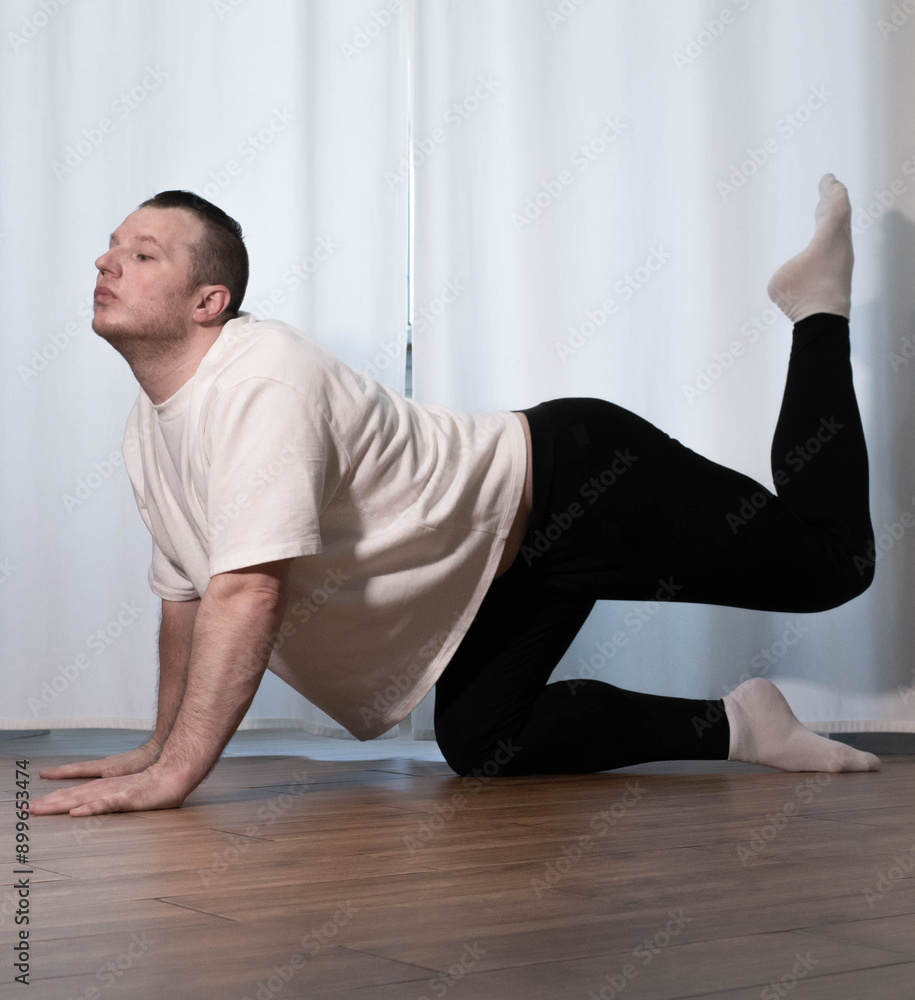 Fototapeta premium Home yoga pose workouts. A man performs sports exercises with his legs and arms. Male athlete stretches.