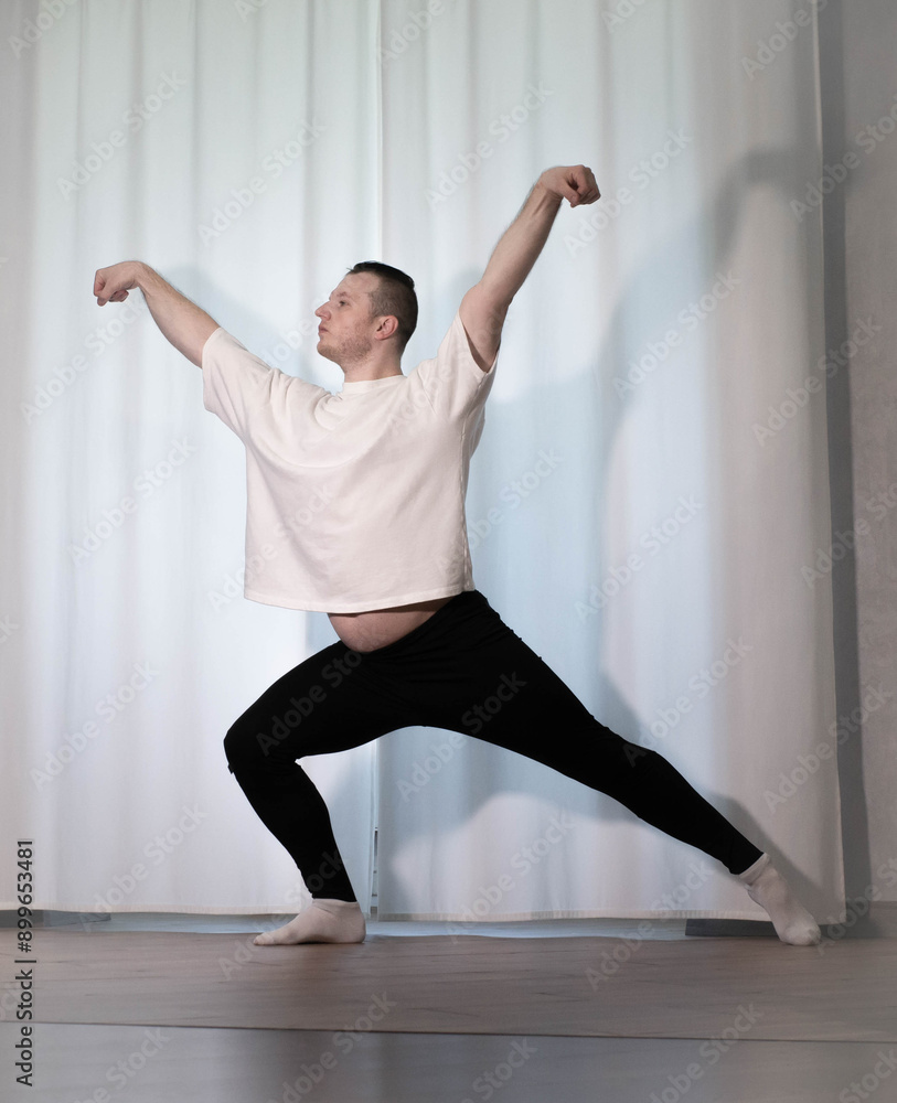 Home workouts in yoga poses. A man performs sports dance exercises with his legs and arms. Pilates stretching Home workouts in yoga poses. A man performs sports dance exercises with his legs and arms. Pilates stretching