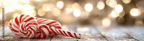 A festive candy cane rests on a wooden table, surrounded by soft, sparkling lights, perfect for holiday-themed imagery.