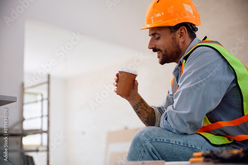 Happy worker taking coffee break during home renovating process. photo