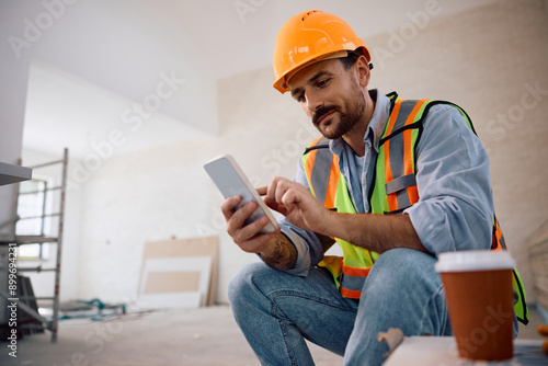 Foto Smiling worker using smart phone at construction site.
