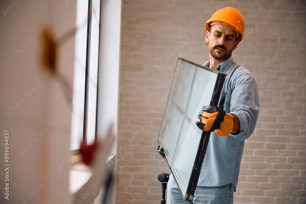 Construction worker changing windows during house renovation. Construction worker changing windows during house renovation.