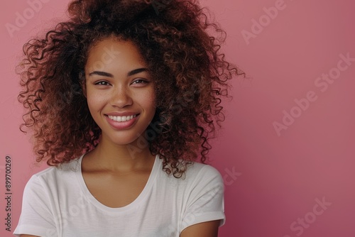 Young cheerful beautiful woman looking aside and smile in front of soft pink background. Gorgeous curly hair african american teen age girl in trendy clothes with crossed arms stand, Generative AI © Lens Lullabies