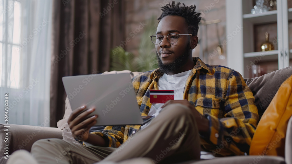 A man is sitting on a couch and looking at a laptop A man is sitting on a couch and looking at a laptop