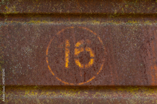 rusty metal plate or sign with number 16 (sixteen)