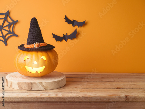 Halloween jack o lantern pumpkin decoration on wooden table over orange wall background photo