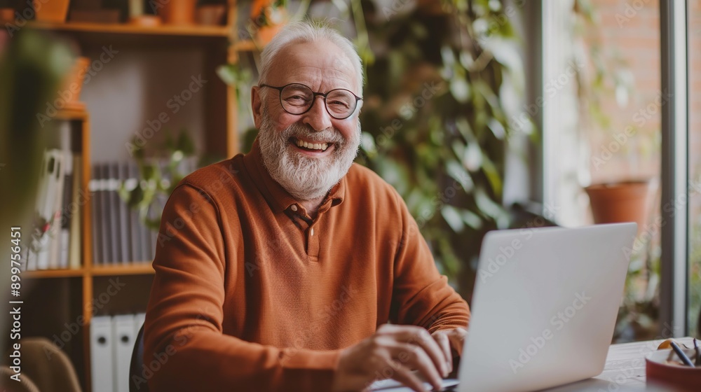 Cheerful senior man working on laptop at home office with bright smile. Mature businessman working remote from home with laptop and files. Cheerful senior man working on laptop at home office with bright smile. Mature businessman working remote from home with laptop and files.